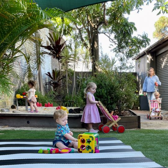  Young children playing with toys in a sandbox and on a mat